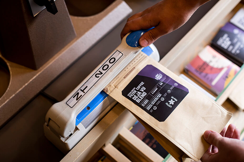 Man sealing a coffee packaging in coffee island store