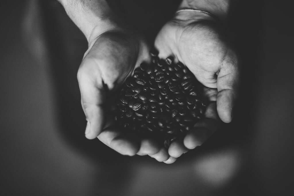 A man holding coffee beans in his hands. 