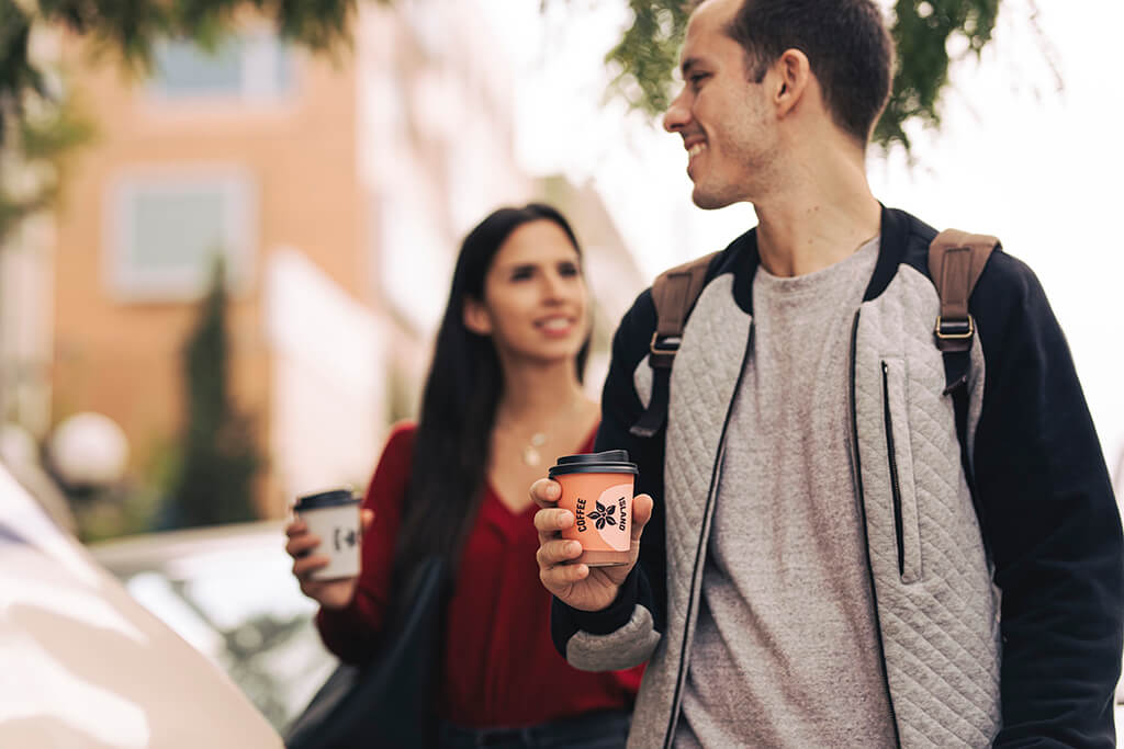 Man and woman enjoying a walk holding their paper cup coffees
