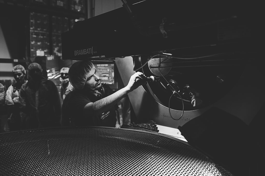 A coffee professional touches the artisan roasting machine