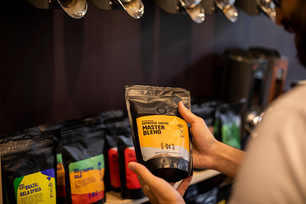 A man holding a master blend coffee packaging inside a Coffee Island store. 