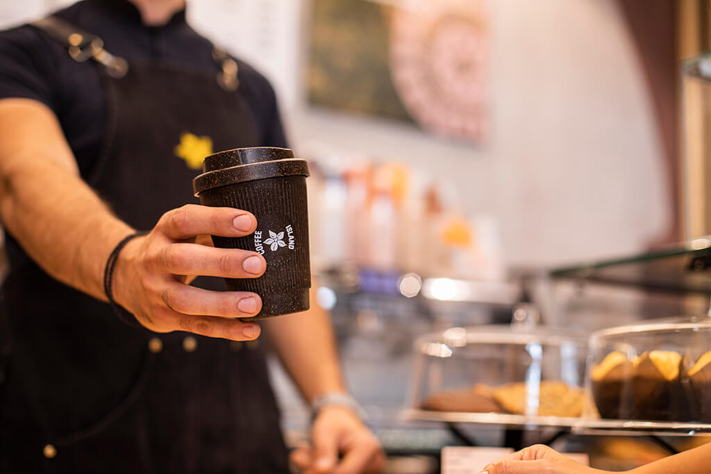 A barristi holding a kaffee form reusable cup