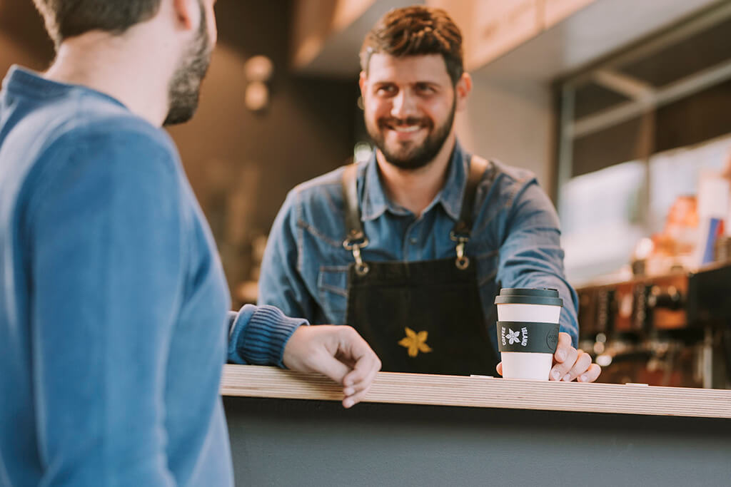 A barristi giving a customer coffee in a reusable cup