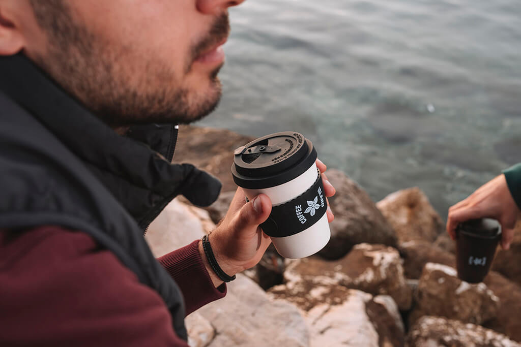 A man drinking tea in a reusable cup from Coffee Island