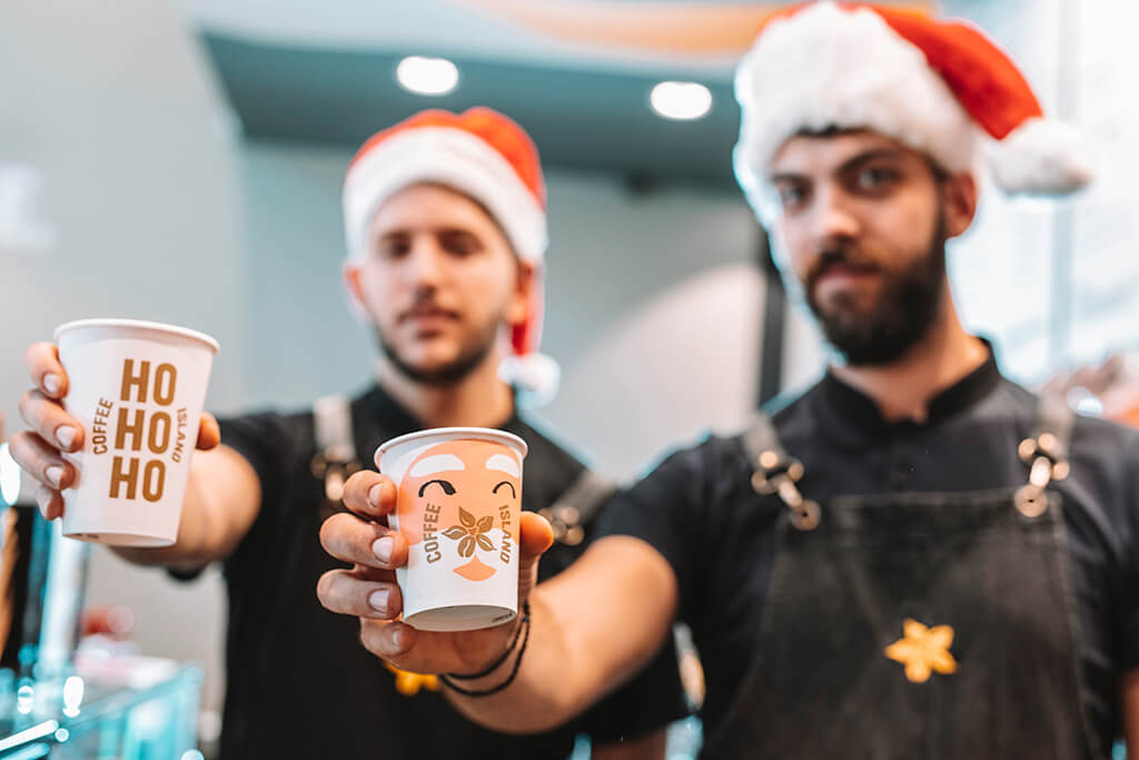 Two baristi men holding Coffee Island Christmas cups