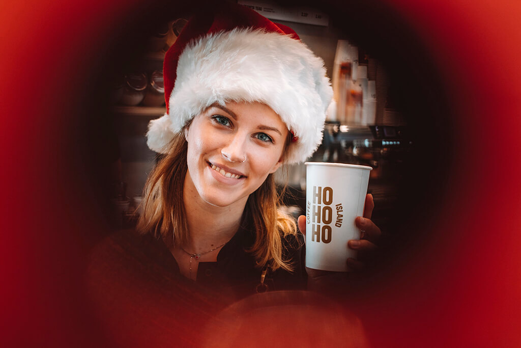 Baristi woman with Christmas spirit holding a Coffee Island Christmas cup