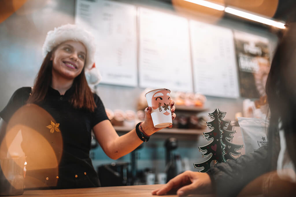 Baristi woman offering coffee in a Coffee Island Christmas cup