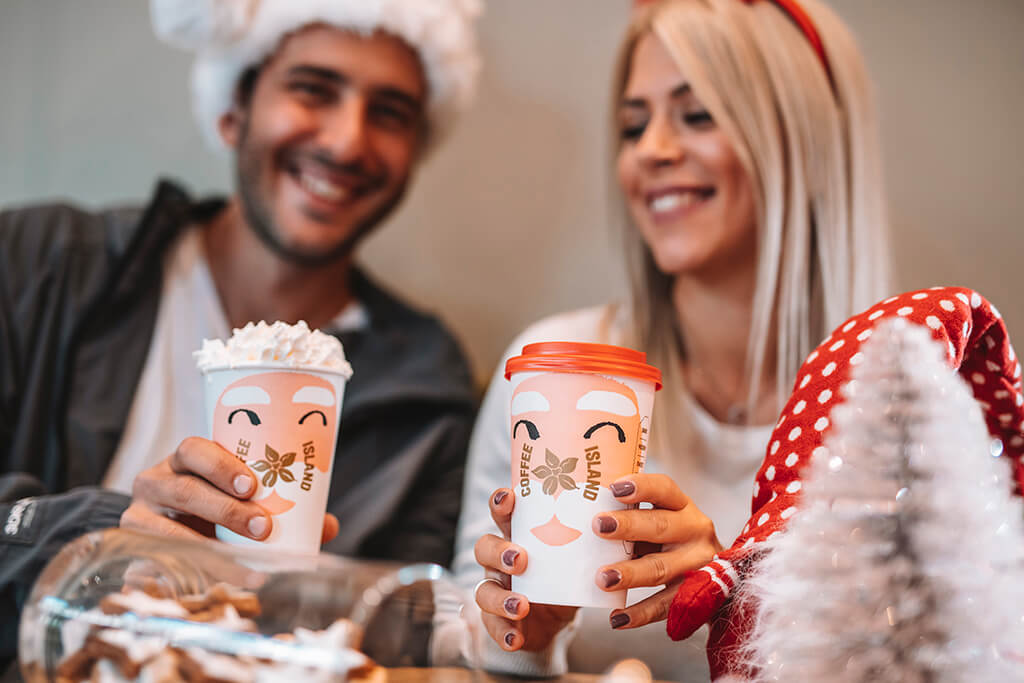 A man and a woman happily enjoying their Coffee Island Christmas beverages