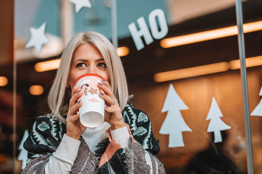 Woman drinking coffee in a Coffee Island Christmas cup