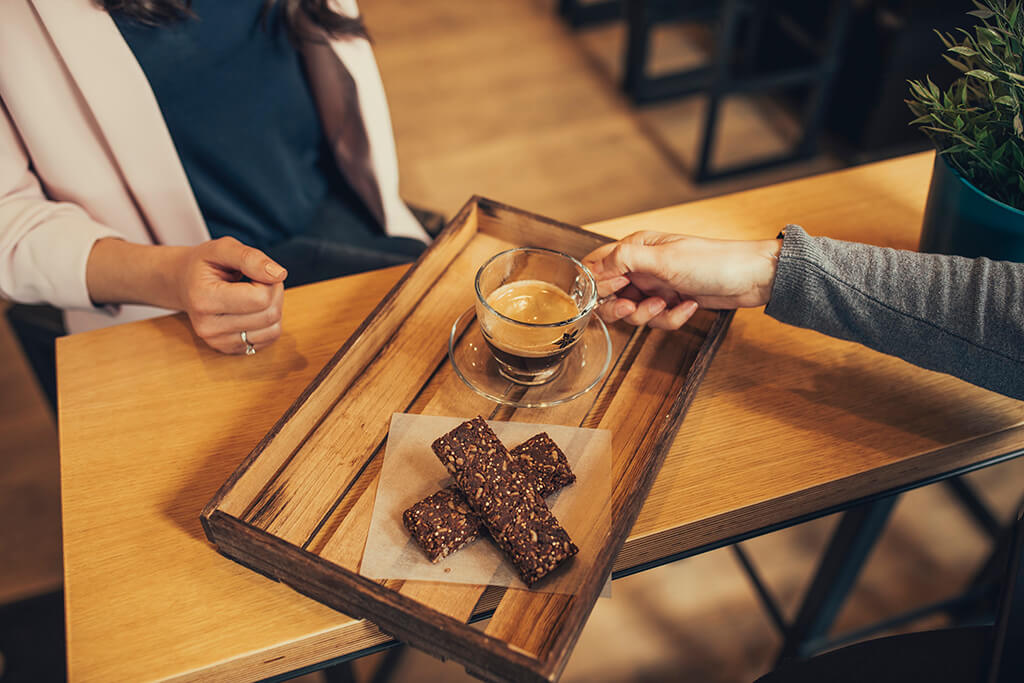 Two people at a Coffee Island store drinking coffee and eating healthy bars. 