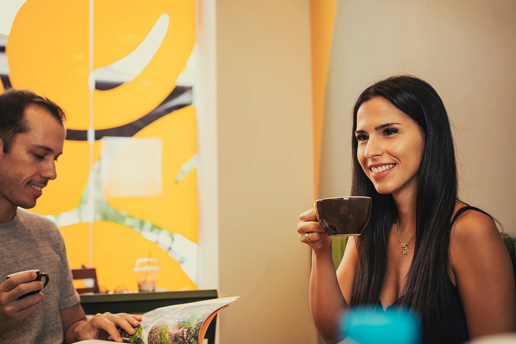 Man and woman enjoying their flat white and Spanish latte coffees at Coffee Island. 
