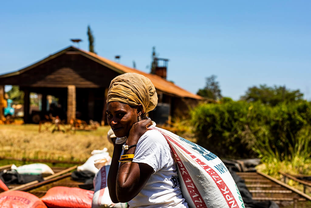 Coffee Island International Women's Day, a woman carrying a sack of coffee beans